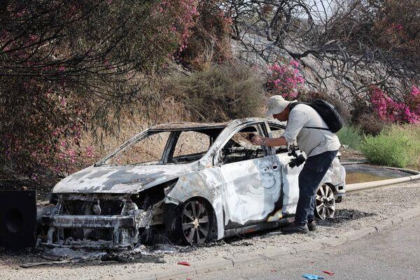 A man takes pictures of a car burned during an infiltration by Palestinian militants from the Gaza Strip, a day after the attack near the southern city of Sderot on October 8, 2023.  (Photo by JACK GUEZ/AFP via Getty Images)