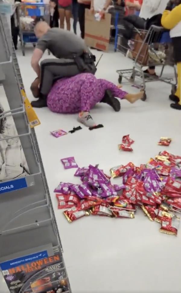 The cop is seen trying to restrain the woman 