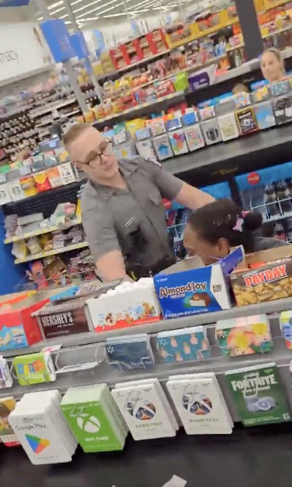The cop is seen trying to restrain the woman, sitting on her