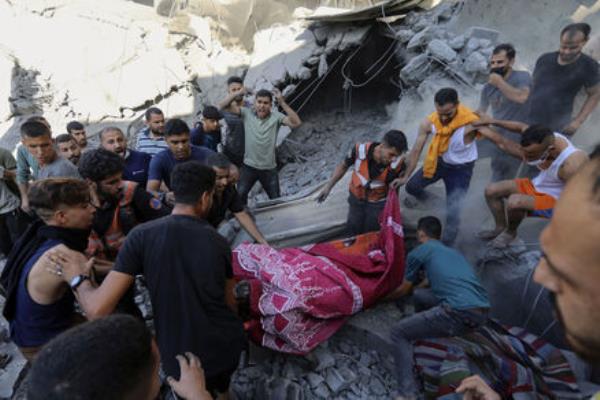 Palestinians carry a dead person from under the rubble of a destroyed house following an Israeli airstrike. Picture: AP Photo/Abed Khaled