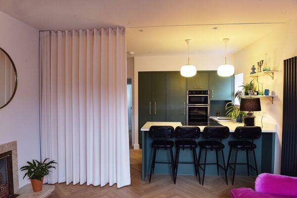  The Kitchen seen from the sitting area with a recessed track for the curtain which seperates the room when guests are staying on the sofabed at 132 Ranelagh Road with interior design by David O'Brien. Photograph Moya Nolan