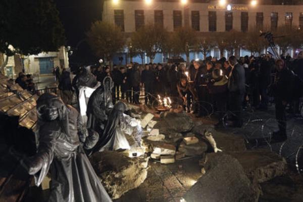 People light candles next to a nativity scene decorated to ho<em></em>nor the victims in Gaza and asking for peace, displayed in Manger Square, adjacent to the Church of the Nativity, in the West Bank town of Bethlehem,